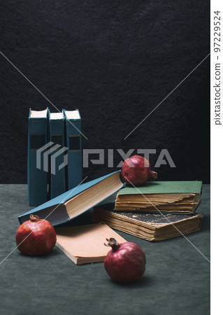 Ripe red pomegranates with books on the table Ripe red pomegranates with books on the table 97229524