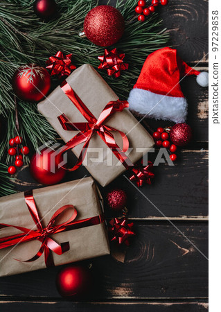 Christmass background gift boxes,red christmas tree toys,Santa hatn and spruce brance on wooden background. 97229858