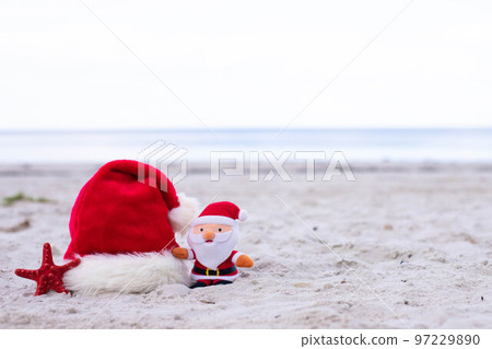 Santa Claus hat,starfish and Santa toy on the beach Santa Claus hat,starfish and Santa toy on the beach 97229890