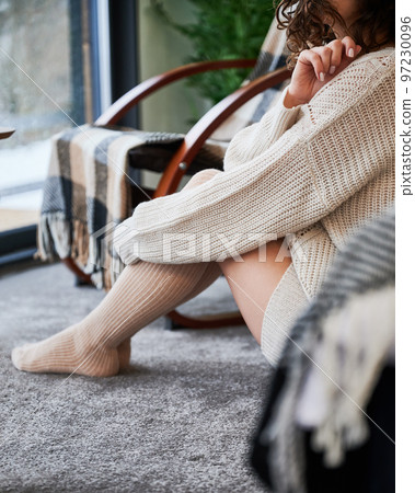 Curly young woman enjoying weekends inside contemporary barn house. Close up view of happy female tourist sitting on floor in new cottage. Curly young woman enjoying weekends inside contemporary barn house. Close up view of happy female tourist sitting on floor in new cottage. 97230096