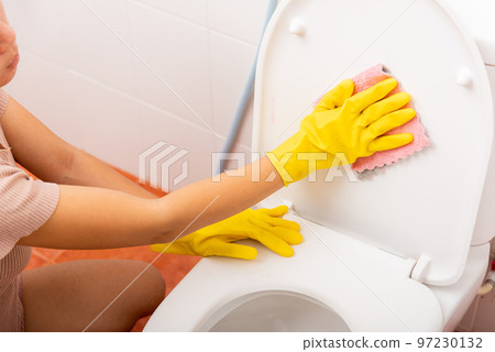 Hands of Asian woman cleaning toilet seat by pink cloth wipe restroom at house, female wearing yellow rubber gloves she sitting and cleanup or washing bathroom, Housekeeper healthcare concept Hands of Asian woman cleaning toilet seat by pink cloth wipe restroom at house, female wearing yellow rubber gloves she sitting and cleanup or washing bathroom, Housekeeper healthcare concept 97230132