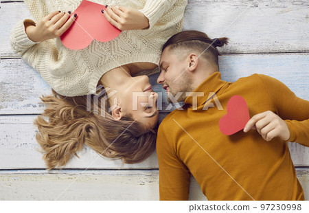 Happy young man and woman in love lying on floor during photo session on Valentine's Day Happy young man and woman in love lying on floor during photo session on Valentine's Day 97230998