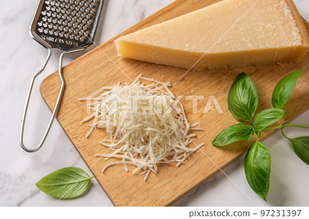 Grated grana padano cheese on a cutting board. 97231397