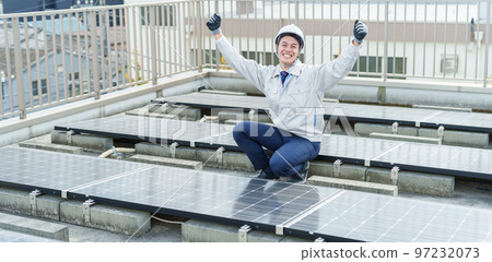 A male worker doing a guts pose in front of the solar panel A male worker doing a guts pose in front of the solar panel 97232073