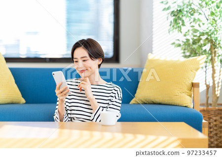 A woman who operates a smartphone in the living room 97233457