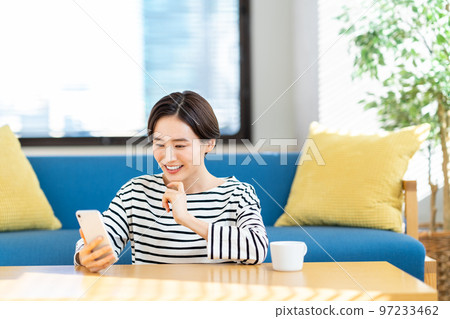 A woman who operates a smartphone in the living room 97233462