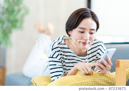 A woman operating a smartphone with a sofa A woman operating a smartphone with a sofa 97233671