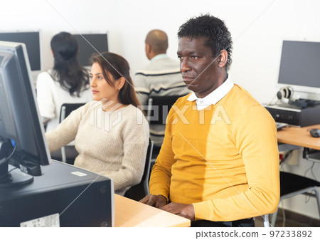 Young adult man studying in computer class Young adult man studying in computer class 97233892