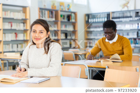 Young adult woman studying in public library Young adult woman studying in public library 97233920