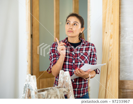 Woman foreman checks the completed construction work on drawing 97233967