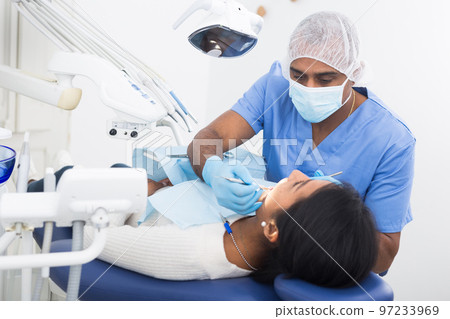 Dentist male in uniform is examinating of female in clinic 97233969