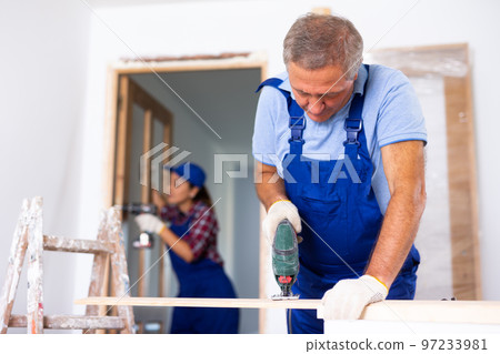 Man builder using fretsaw during home improvement works 97233981