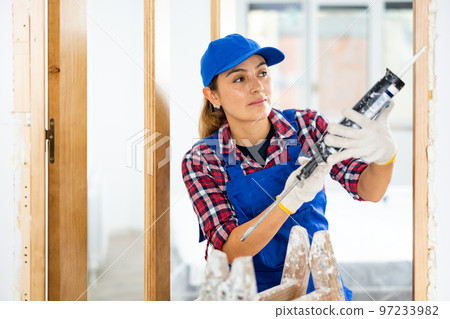 Woman builder using spray foam around doorway Woman builder using spray foam around doorway 97233982