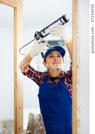 Female professional door installer fills gaps with mounting foam 97234050