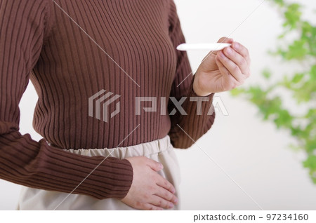 一個女人在看試驗藥時摸著她的肚子 一個女人在看試驗藥時摸著她的肚子 97234160