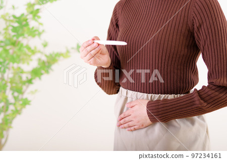 一個女人在看試驗藥時摸著她的肚子 一個女人在看試驗藥時摸著她的肚子 97234161