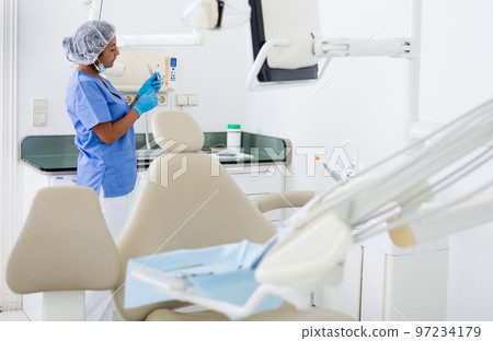 Female dentist checking and arranging tools in dental office 97234179