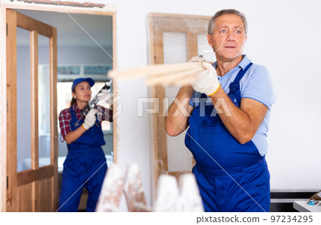 Repairman carrying bunch of wooden planks 97234295