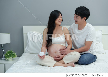 pregnant couple stroking apply cream on belly for beauty moisturizing skin on bed pregnant couple stroking apply cream on belly for beauty moisturizing skin on bed 97235129
