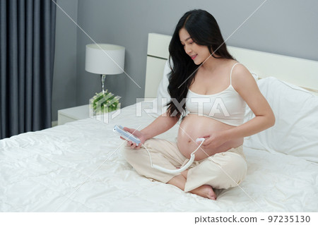 pregnant woman using fetal droppler device to listening baby heartbeat pregnant woman using fetal droppler device to listening baby heartbeat 97235130