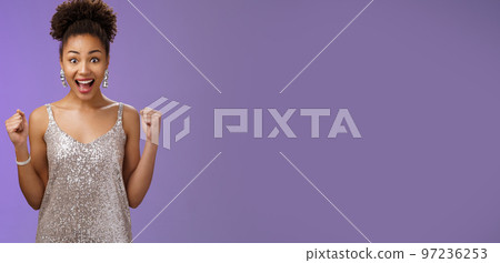 Impressed surprised thrilled joyful charming elegant african-american woman winning money casino achieve success yelling happily raise fists victory triumph gesture cheering gladly blue background 97236253