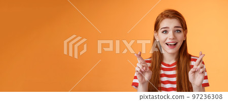 Excited hopeful redhead girl hope win lottery, smiling optimistic, look faith, believe dream come true, cross fingers good luck, make wish, anticipate good news, praying fortune, orange background Excited hopeful redhead girl hope win lottery, smiling optimistic, look faith, believe dream come true, cross fingers good luck, make wish, anticipate good news, praying fortune, orange background 97236308