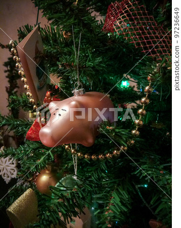 a glass toy in the form of a pink pig hangs on a decorated Christmas tree a glass toy in the form of a pink pig hangs on a decorated Christmas tree 97236649