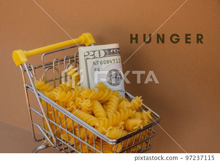 HUNGER text against Shopping trolley cart Filled With Pasta with 20 US dollar paper money banknote on Beige background. Food and groceries shopping price increase, Rising food cost food crisis HUNGER text against Shopping trolley cart Filled With Pasta with 20 US dollar paper money banknote on Beige background. Food and groceries shopping price increase, Rising food cost food crisis 97237115