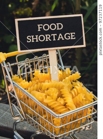 FOOD SHORTAGE text on Blackboard label Shopping trolley cart Filled With Pasta on agriculture background. Food and groceries shopping price increase, Rising food cost food crisis inflation 97237119