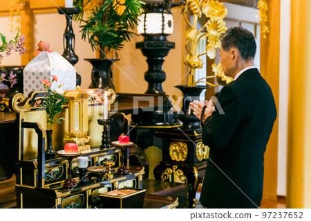 An elderly woman in mourning clothes standing on an incense stand at a funeral (incense) An elderly woman in mourning clothes standing on an incense stand at a funeral (incense) 97237652