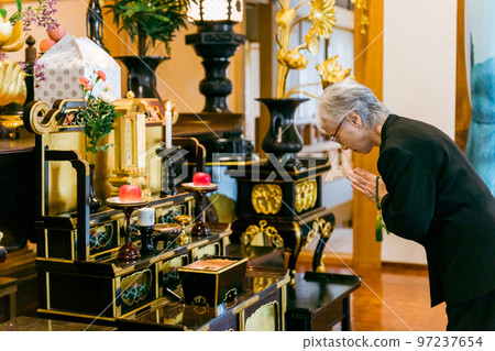 An elderly woman in mourning clothes standing on an incense stand at a funeral (incense) An elderly woman in mourning clothes standing on an incense stand at a funeral (incense) 97237654