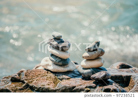 Balanced rock pyramid on pebbles beach, sunny day and clear sky at sunset. Golden sea bokeh on background. Selective focus, zen stones on sea beach, meditation, spa, harmony, calm, balance concept. Balanced rock pyramid on pebbles beach, sunny day and clear sky at sunset. Golden sea bokeh on background. Selective focus, zen stones on sea beach, meditation, spa, harmony, calm, balance concept. 97238521