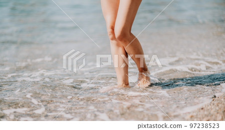 A woman walks along the beach, legs close-up. Barefoot woman sta A woman walks along the beach, legs close-up. Barefoot woman sta 97238523