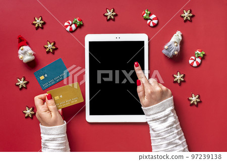 top view female hands holding credit card, tablet with black digital screen, Christmas decor on red table Flat lay Holiday shopping list, Happy New Year, online shop, chooses gifts, makes purchases. top view female hands holding credit card, tablet with black digital screen, Christmas decor on red table Flat lay Holiday shopping list, Happy New Year, online shop, chooses gifts, makes purchases. 97239138
