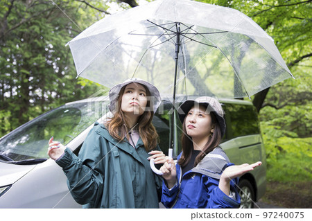 Female friends disappointed to find it raining after arriving at the campsite Outdoor image Female friends disappointed to find it raining after arriving at the campsite Outdoor image 97240075