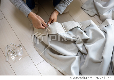 Young woman unhooking curtains 97241262