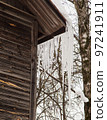 Sharp, frozen icicles hang on the corner of the roof, winter or spring.  97241911