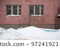 A small snowdrift on the background of the brick wall of the building. 97241921