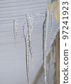 Multiple, melting icicles hanging through cracks, spring or winter.  97241923