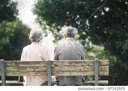 Rear view of a senior couple sitting on a park bench 97242920