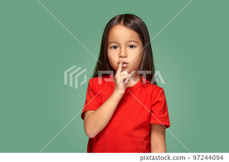 girl placing finger on lips asking shh, quiet, silence 97244094