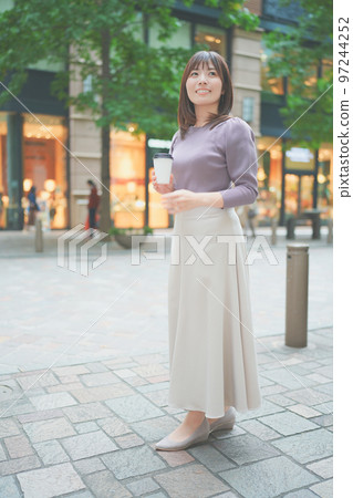拿著一杯咖啡在城市裡散步的女人 拿著一杯咖啡在城市裡散步的女人 97244252