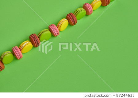 Colored macaron or macaroon, sweet meringue-based confection on green background. Close-up, copy space. Colored macaron or macaroon, sweet meringue-based confection on green background. Close-up, copy space. 97244635