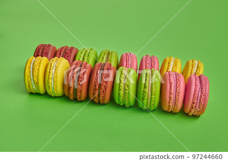 Colored macaron or macaroon, sweet meringue-based confection on green background. Close-up, copy space. Colored macaron or macaroon, sweet meringue-based confection on green background. Close-up, copy space. 97244660