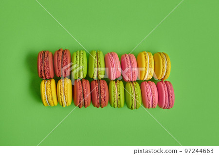 Colored macaron or macaroon, sweet meringue-based confection on green background. Close-up, copy space. 97244663