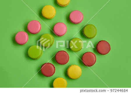 Colored macaron or macaroon, sweet meringue-based confection on green background. Close-up, copy space. Colored macaron or macaroon, sweet meringue-based confection on green background. Close-up, copy space. 97244684