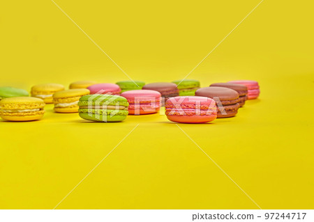 Colored macaron or macaroon, sweet meringue-based confection on yellow background. Close-up, copy space. 97244717
