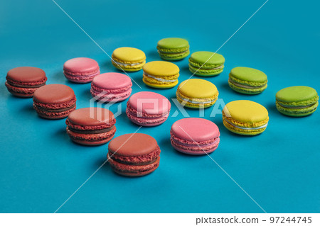 Colored macaron or macaroon, sweet meringue-based confection on blue background. Close-up, copy space. Colored macaron or macaroon, sweet meringue-based confection on blue background. Close-up, copy space. 97244745