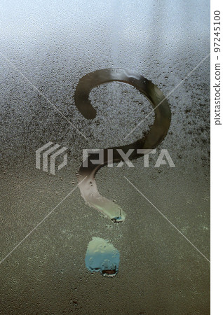 A question mark is drawn on glass with condensation, the effect of fogged windows and glass. A question mark is drawn on glass with condensation, the effect of fogged windows and glass. 97245100