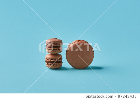 Close-up studio shot of tasty chocolate macarons on blue background. 97245433